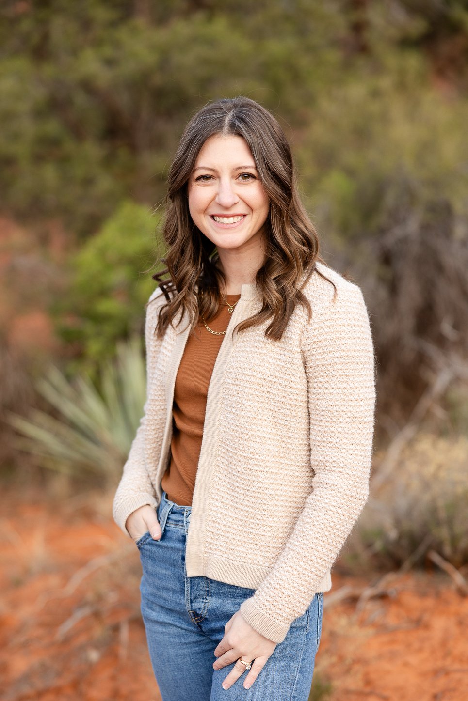 A female with brown hair in jeans and a tan cardigan sweater, smiling and  standing in the desert

Photo by Kilee Covert Photography